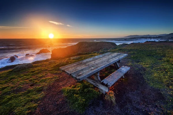 Bank und Tisch am Strand bei Sonnenuntergang — Stockfoto