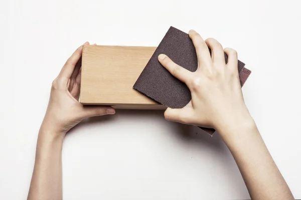 woman hand sanding wooden block with sandpaper