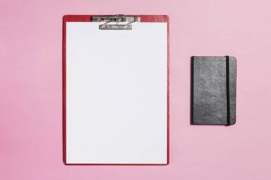 Kırmızı Pano pembe arka plan üstünde defter ile