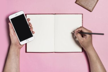 pembe bir arka plan üzerine bir kitap yazma ile bir telefon tutarak.