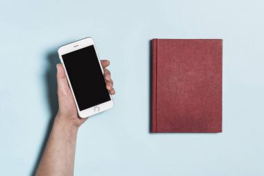 holding bir telefon ve mavi arka plan üzerinde kırmızı kitap.