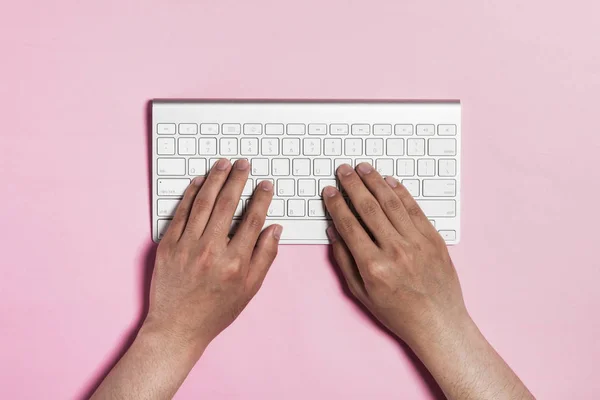 hand typing keyboard on pink background.