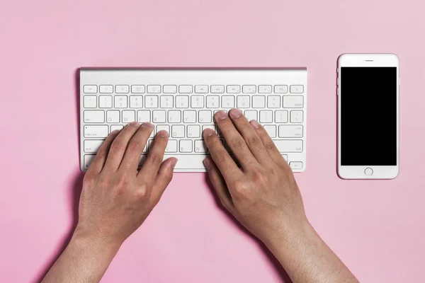 hand typing keyboard on pink background.