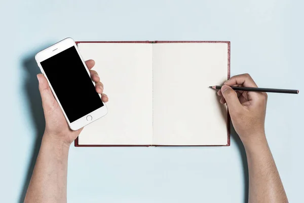 Segurando um telefone com a escrita de um livro sobre fundo azul . — Fotografia de Stock