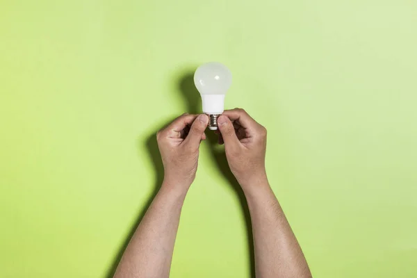 Holding a light bulb by hand. eco concepts. green background, isolated