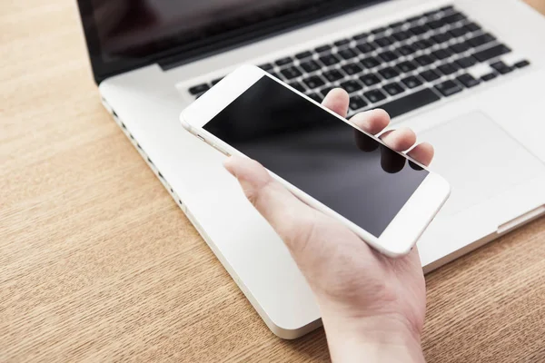 telefonu ve laptop yaz ahşap masanın üzerinde tutan adam.