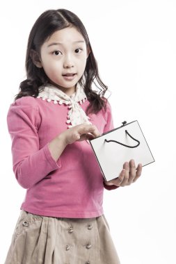 Bir Asya (Kore, Japon, Çinli) kız (çocuk, öğrenci, çocuk, kadın, erkek) pembe bluz tutun ve watch(see) giymiş bir boş (boş, boş, içi boş) alışveriş çantası (kağıt torba) beyaz izole.