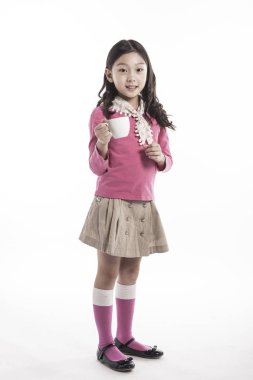 Seramik bardak tutan bir kız. (pembe bluz giyiyor)