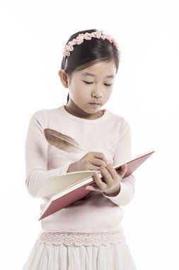 Beyaz arka plan üzerinde izole stüdyoda tüy pan duran bir kitap tutan küçük kız