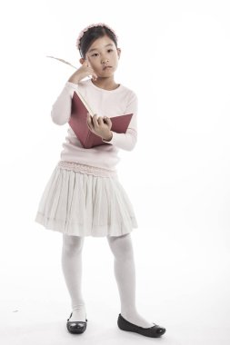 Beyaz arka plan üzerinde izole stüdyoda tüy pan duran bir kitap tutan küçük kız