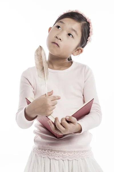 小女孩拿着一本书与羽毛平底锅 当站立在演播室时 隔绝在白色背景 — 图库照片