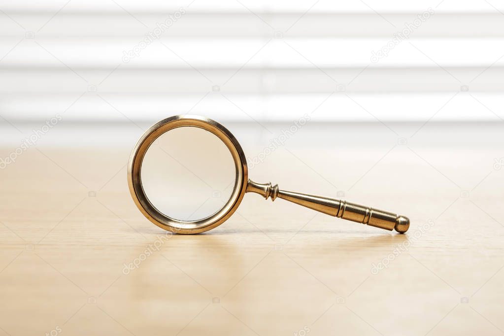 antique magnifying glass on wooden desk.
