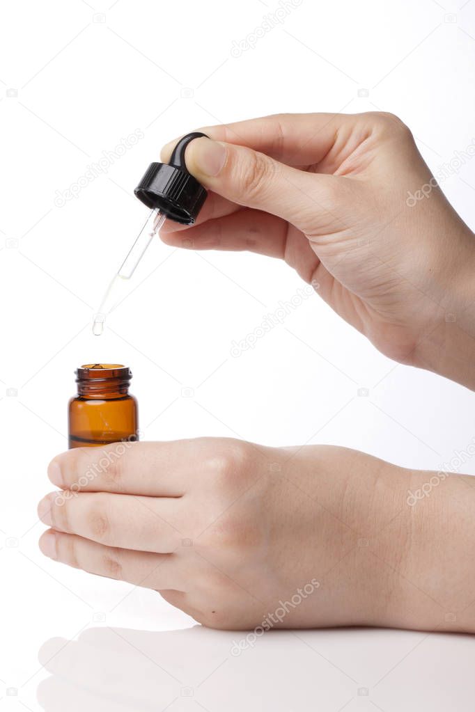 Essential oil dropping from pipette to the bottle. Essence liquid cosmetic. Syrup. Perfume.Aromatherapy. Isolated on white.