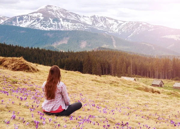 Het meisje mediteert op gras tussen bloemen in Bergen — Stockfoto