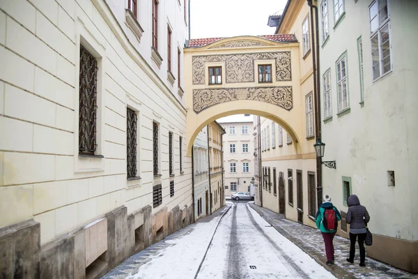 Two girls walking down street under arch