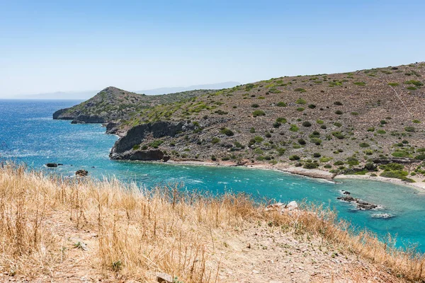 Spinalonga Adası tepesinden görüntüleyin. Kayalar ve Kalydon Adası önünde mavi deniz.