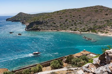 Spinalonga Adası tepesinden görüntüleyin. Tekne ve Kalydon Adası önünde mavi denize sıfır.