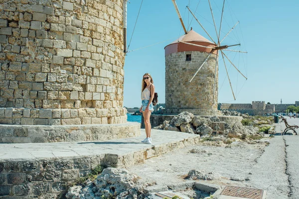 Jong mooi meisje in spijkerbroek, T-shirt, witte sneakers met zonnebril — Stockfoto