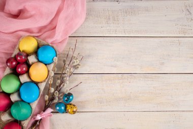 Bayram için, dalları ve ahşap arka planda pembe havlusu olan bir arabada paskalya yumurtası. Boşluğu kopyala