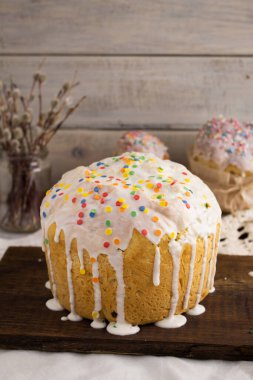 Paskalya bayramı için rengarenk şeker parçalarıyla süslenmiş söğüt dalları ve ahşap arka planda söğüt ağacı tarzı bir paskalya pastası.