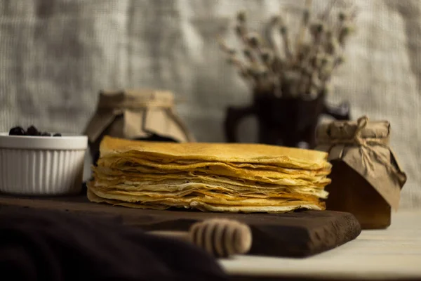 A stack of fresh Russian pancakes for Shrovetide with jam, honey and willow branches. Pancake week. On a wooden Board in the Russian style — Stock Photo, Image