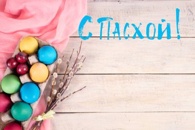 Paskalya için dalları ve ahşap arka planda pembe havlusu olan bir arabada boyanmış yumurta. Rusça 