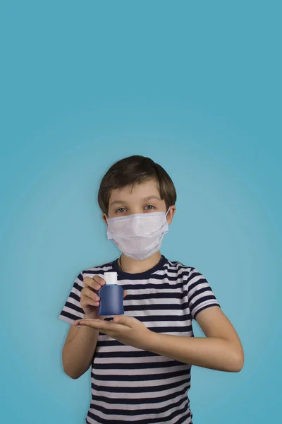 Un niño con una máscara médica sobre un fondo azul. Mano antiséptica. Alcohol para las manos. Protección contra virus y enfermedades, desinfectante de manos . —  Fotos de Stock