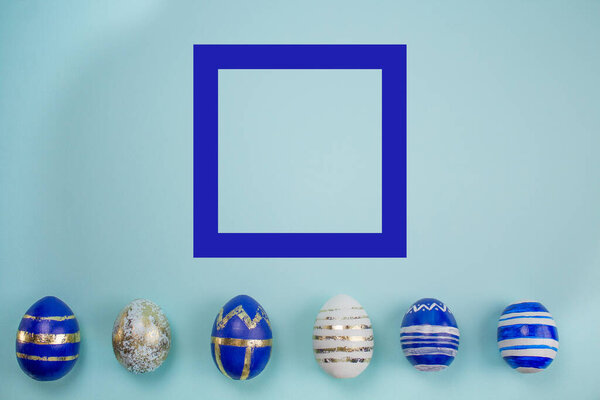 Happy Easter card with copy space. Frame with blue and white eggs with gold patterns on blue background