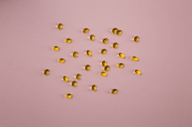 Pembe arka planda D vitamini kapsülleri. Üst görünümü kapat