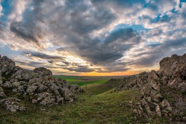 Yeşil bitki örtüsü, kayalar ve mavi bir günbatımı gökyüzü bulutlu, Dobrogea, Romanya güzel manzara