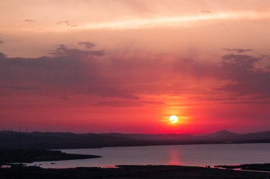 Göl üzerinde rüzgar türbinleri ile bulutlu renkli gün batımı,Enisala, Dobrogea, Romanya