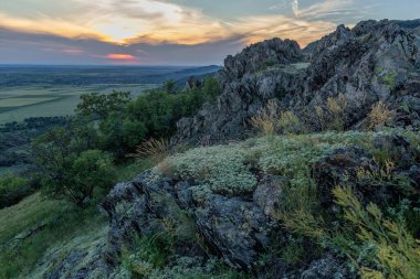 Günbatımı gökyüzü ve ilkbaharda kayalıklarda beyaz çiçeklerle güzel manzara, Dobrogea, Romanya