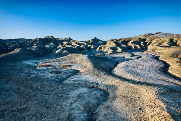 Beautiful lunar landscape with golden light at sunset over the muddy volcanoes, Paclele, Berca, Buzau County, Romania