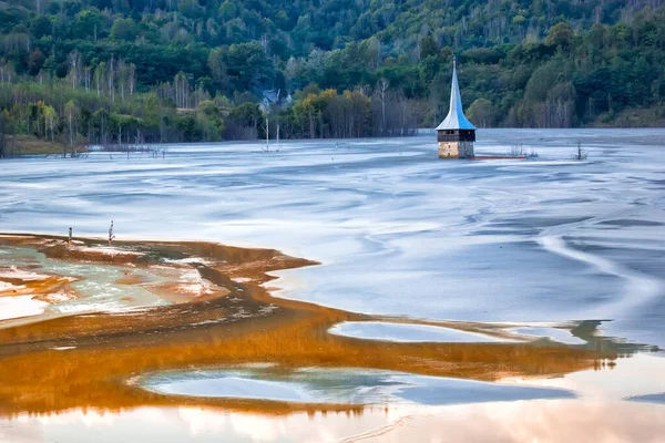 Colorful landscape of a flooded church in toxic polluted lake due to copper mining, Geamana Village, Sesii Valley, Romania