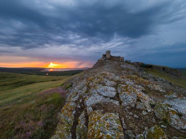 Enisala 'nın eski kalesi Dobrogea, Romanya' nın üzerinde fırtına bulutlarıyla güzel bir manzara ve dramatik bir gün batımı.