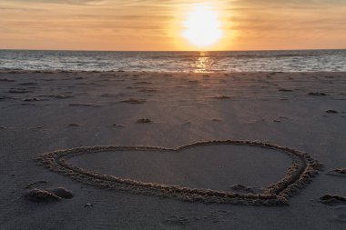 Kumsalda güzel bir gün batımı Kumda ahşap kazıklar ve kalplerle Petten, Hollanda, Hollanda, Kuzey Denizi