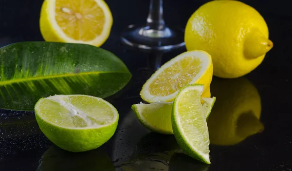 Lima y limón sobre fondo negro —  Fotos de Stock