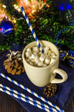 Noel arkaplanında marşmelov olan bir bardak içki.