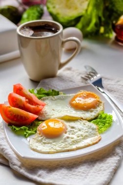 Bir tabakta domatesli iki yumurtadan kızarmış yumurta.