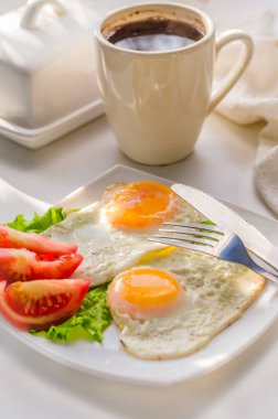 Bir tabakta domatesli iki yumurtadan kızarmış yumurta.