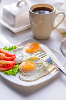 Bir tabakta domatesli iki yumurtadan kızarmış yumurta.