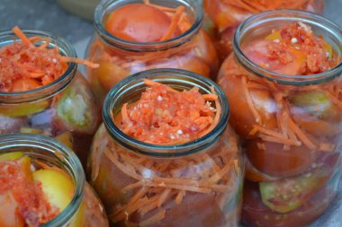 Ev yapımı. Kış için kuru sıkı. Salamuraya yatırılmış. Kavanozda rendelenmiş havuç, kırmızı ve sarı domates.