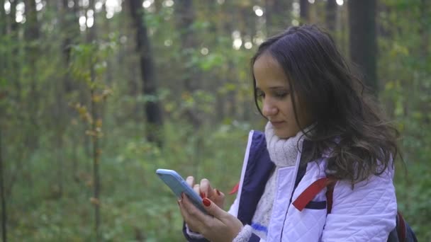 Flickan tittar karta på telefonen i skogen — Stockvideo