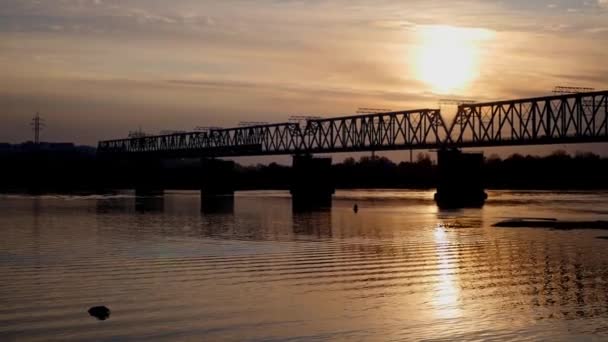 Laissant le train de l'autre côté de la rivière au coucher du soleil — Video