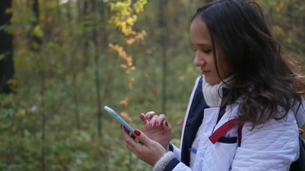 Ela escreve ao telefone na floresta — Vídeo de Stock