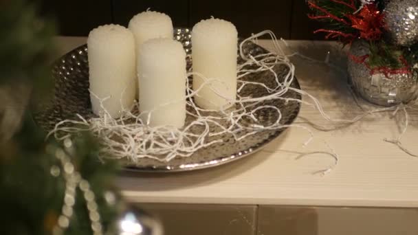 Διακοσμημένο χριστουγεννιάτικο δέντρο στο προσκήνιο με το κίνημα για τα κεριά σε ένα πιάτο με γιρλάντες — Αρχείο Βίντεο