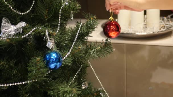 Μπάλα κόκκινη γυναικεία χέρια που κρέμονται από ένα χριστουγεννιάτικο δέντρο — Αρχείο Βίντεο