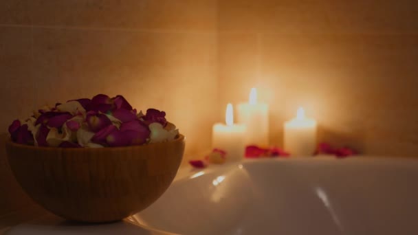 Пелюстки троянд у вазі у ванній на тлі палаючих свічок, 4k — стокове відео