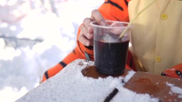 Mooie meisje in kostuum tijgers, warm drinken Glühwein uit een plastic beker in een café in de open winter, 4k — Stockvideo