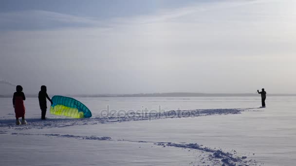 Meisje op een bevroren meer in de winter te helpen Kitesurf verheffen in de hemel, 4k — Stockvideo